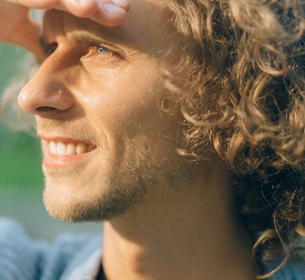 A man smiling and stretching outdoors, looking energized and healthy.
